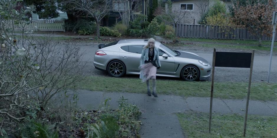 Alice steps out of the car and begins approaching the house.