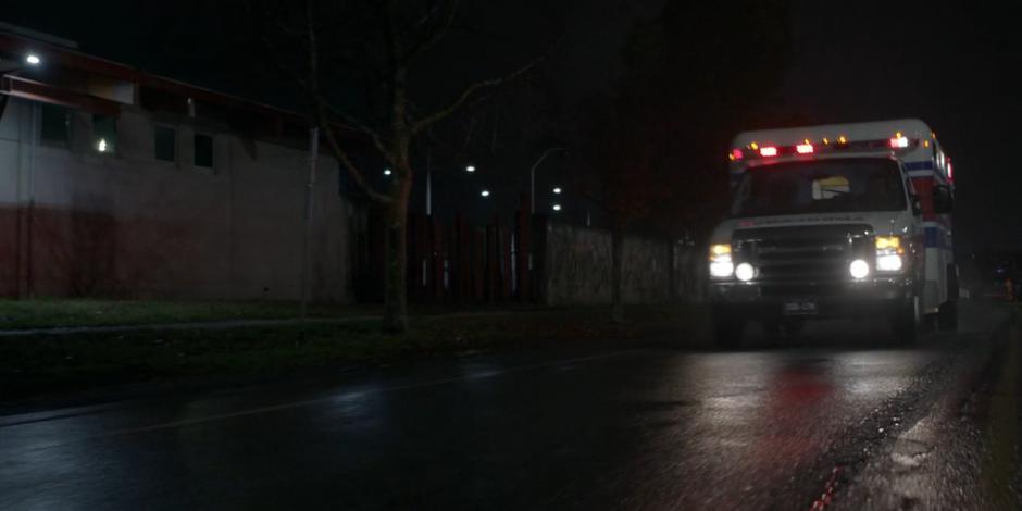 The ambulance speeds down the street at night.