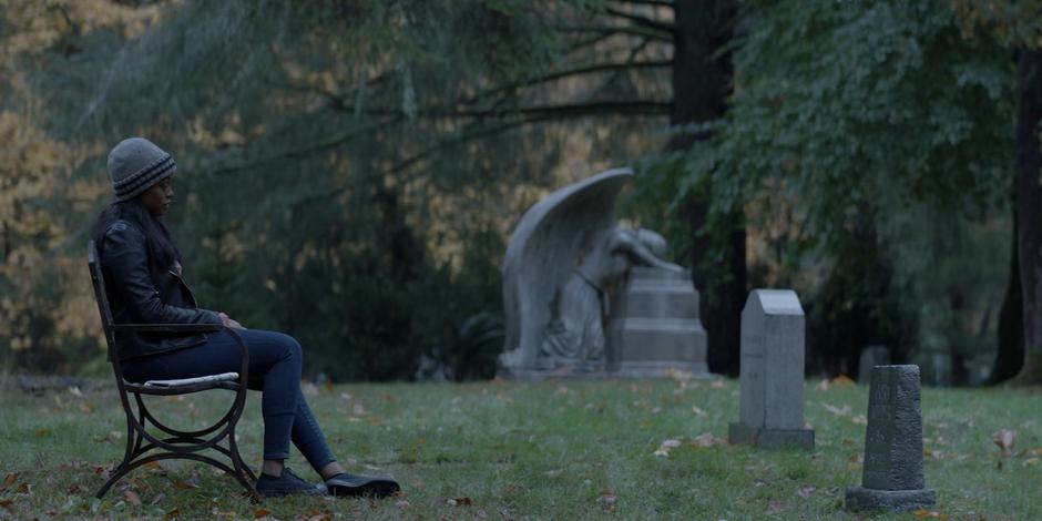 Ryan talks to her mother Cora's gravestone while sitting on a bench.