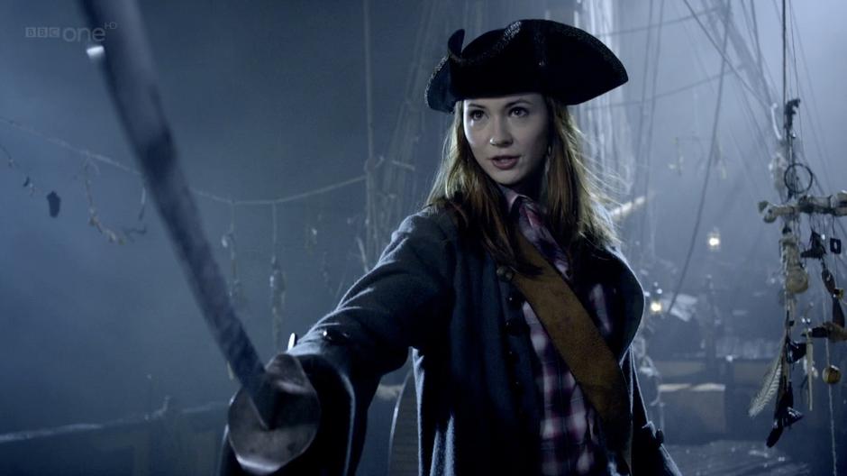 Amy threatens the crew with a sword to save the Doctor.