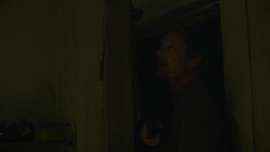 Joel carefully opens the door leading into the bunker.