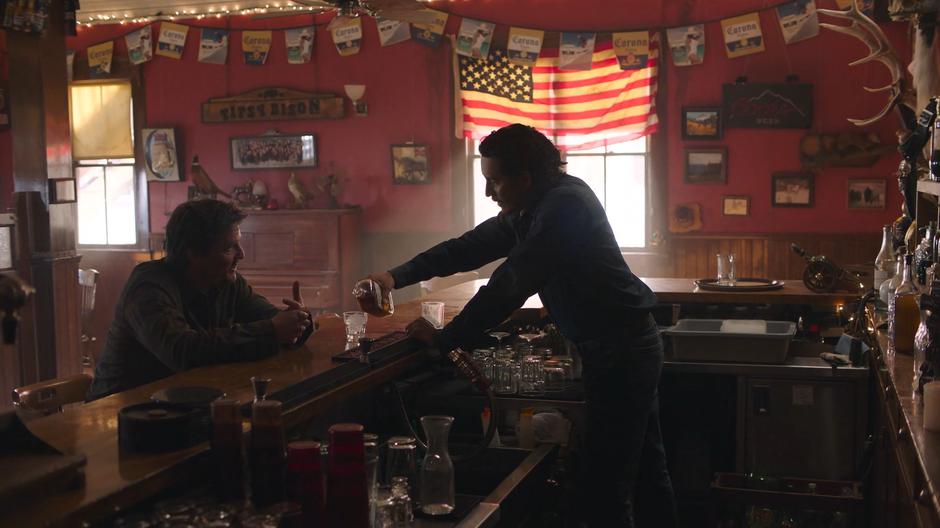 Joel sits at the bar as Tommy pours him a drink.