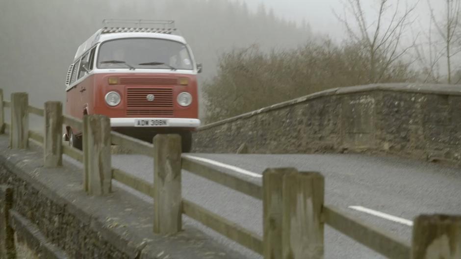 The Doctor drives his van across the bridge.