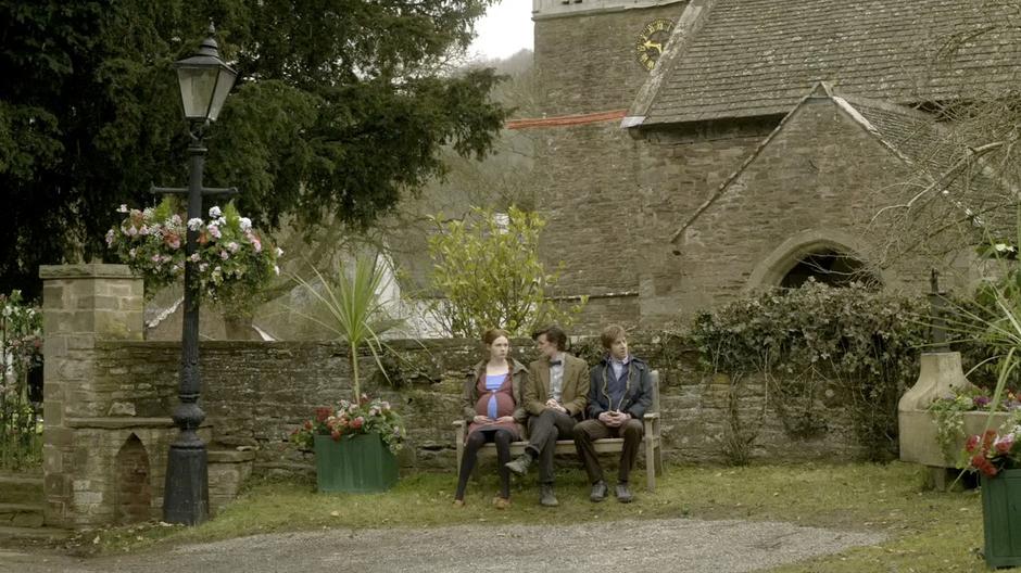 Amy and Rory tell the Doctor about life in the village while sitting on a bench.