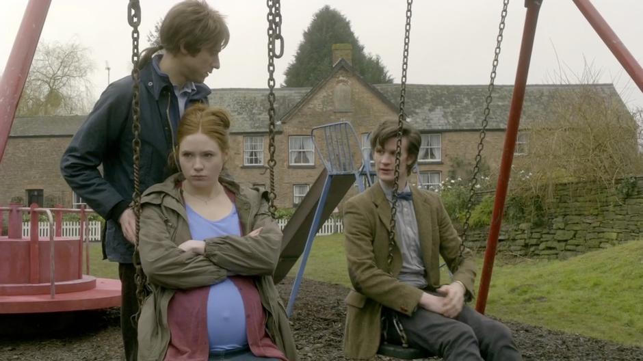 Rory and the Doctor talk while Amy is sullen on a swing set.