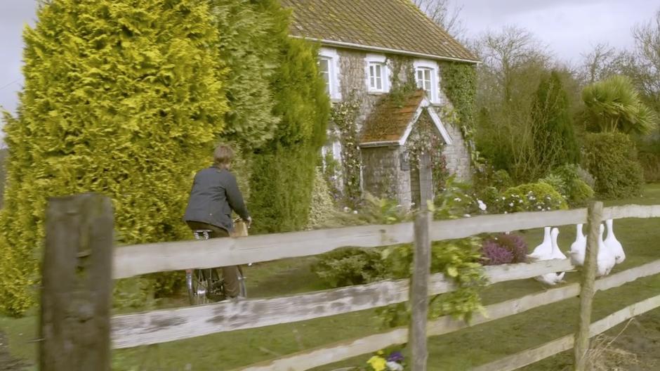 Rory rides up to the front of his and Amy's house on his bicycle.