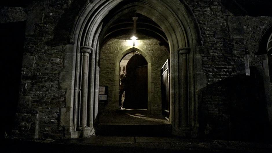 The Doctor looks out the front door of the church into the strange darkness.