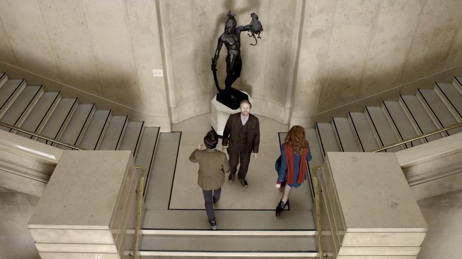 Vincent looks in awe around the museum while Amy and the Doctor walk up the stairs.