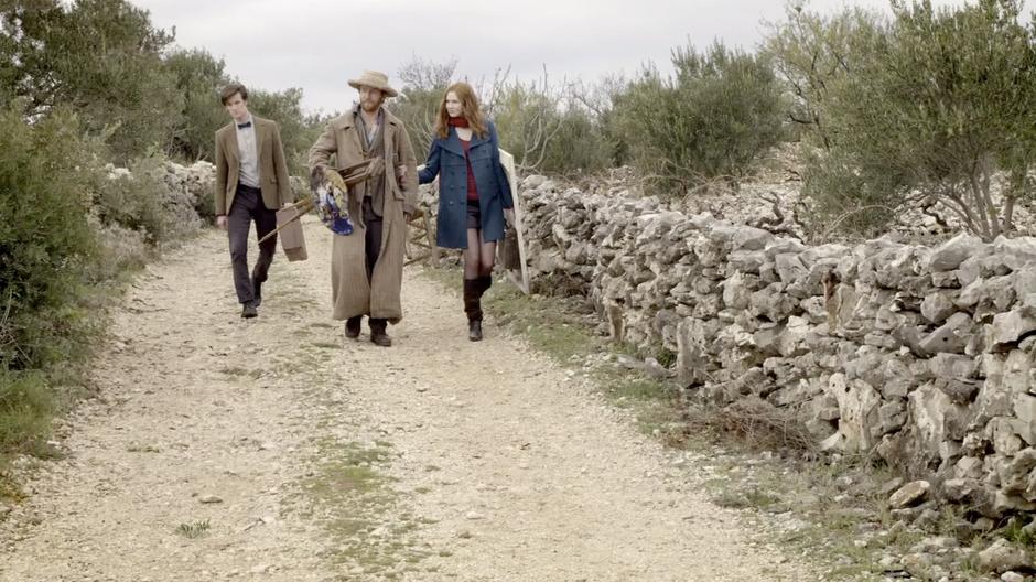 Amy, Vincent, and the Doctor walk down the road towards the church.