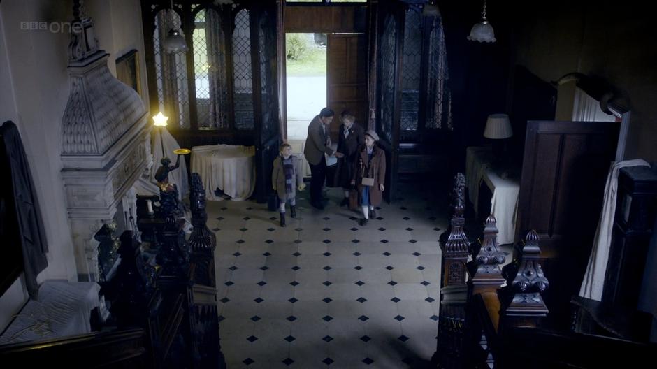 The Doctor shows the Arwell family into the mansion.