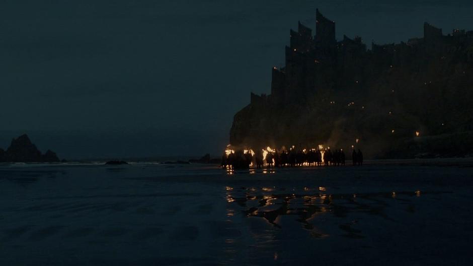 The people of Dragonstone watch Melisandre burn the seven gods.