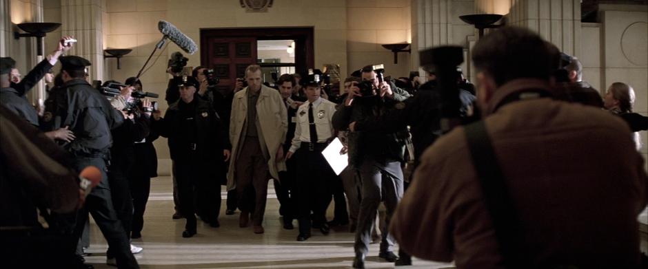 Joe Chill walks from the courtroom surrounded by police.