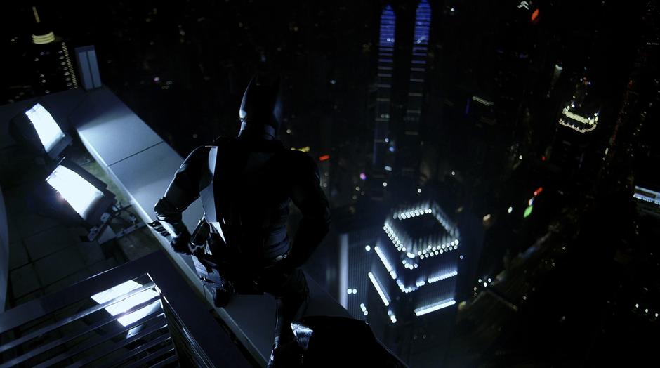 Batman gets ready to jump from an adjacent building to Lau's office building.