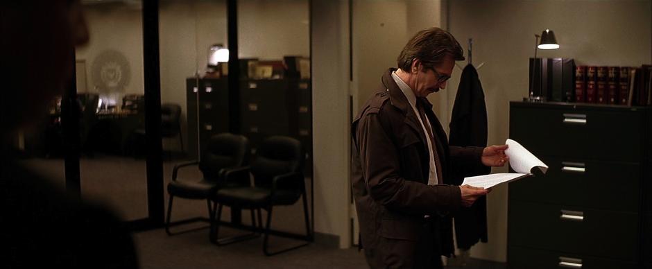 Jim Gordon looks over some documents while Commissioner Leob takes a drink.