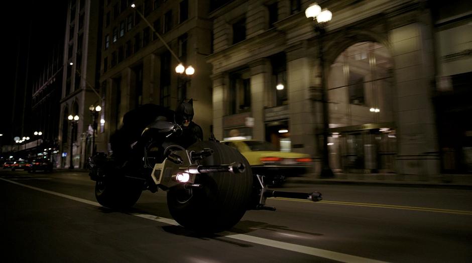 Batman rides his Batcycle towards the Joker.