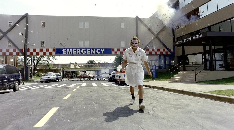 The Joker walks away from the hospital in a nurses outfit while it starts to impede behind him.