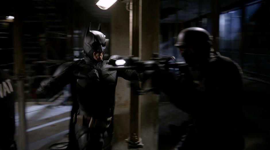 Batman knocks the gun from a SWAT team member.