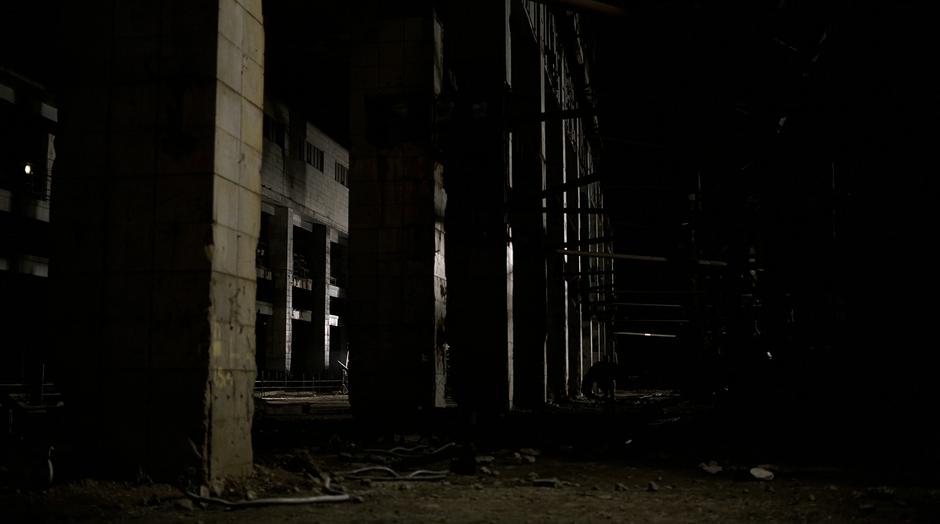 Batman runs through the ruins of the warehouse.