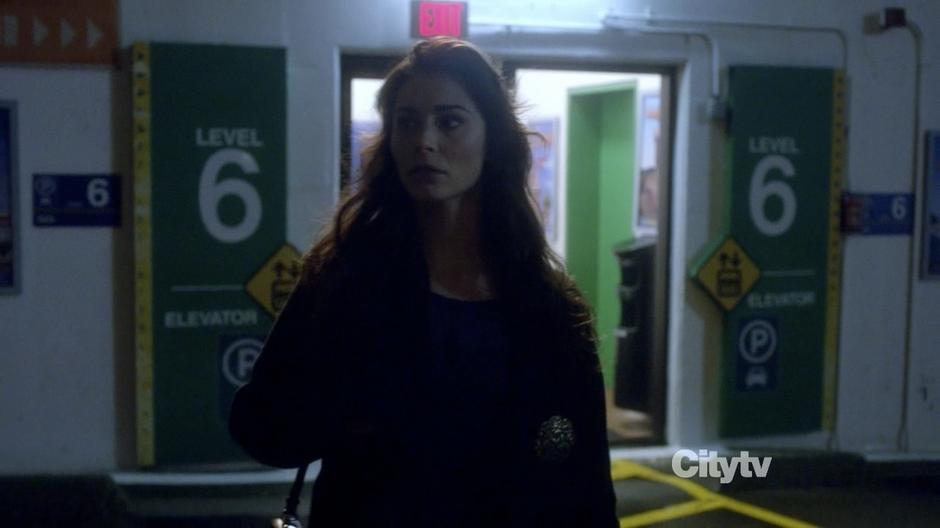 A woman looks around the top floor of the parking garage.