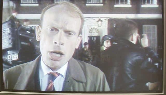 A reporter covers the arrival of people at Downing Street.