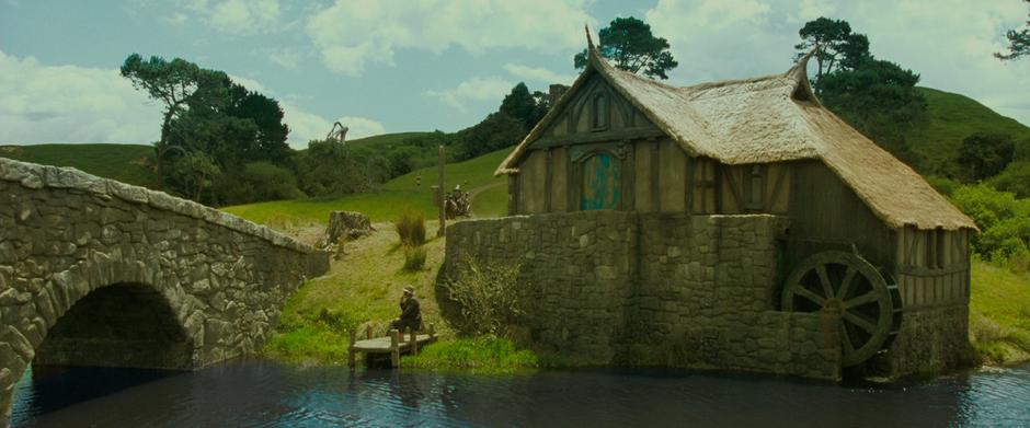 Gandalf drives his cart with Frodo by the Hobbiton mill.
