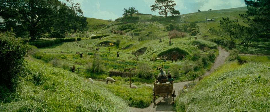 Frodo and Gandalf ride through the center of Hobbiton.