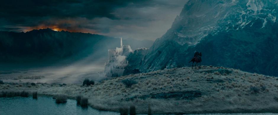 Gandalf rides over a hill and sees Minas Tirith in the distance.