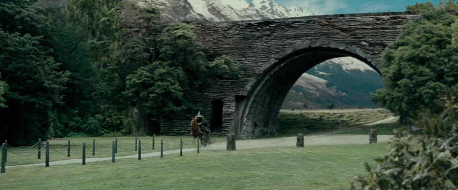 Gandalf rides through the gate in the wall surrounding Isengard.