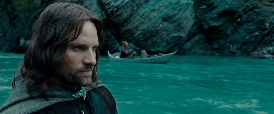 Aragorn looks downriver while the Fellowship travels down the river.