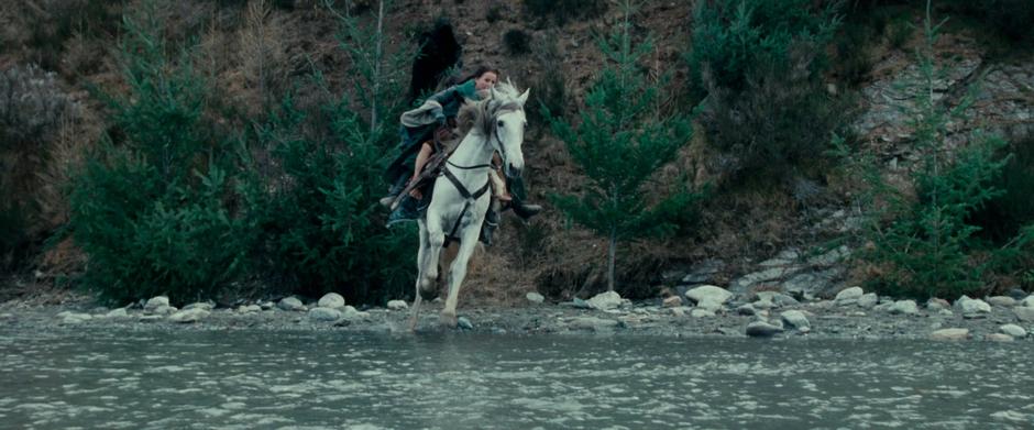 Arwen rides into the ford with Frodo.