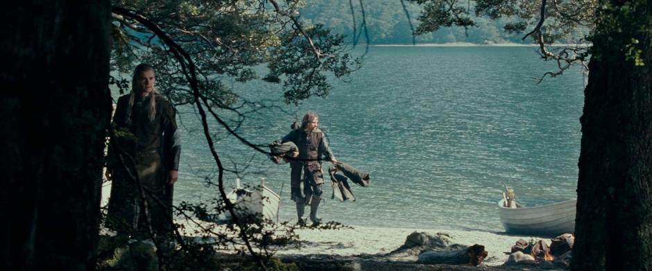 Aragorn unloads his boat while Legolas peers into the woods.