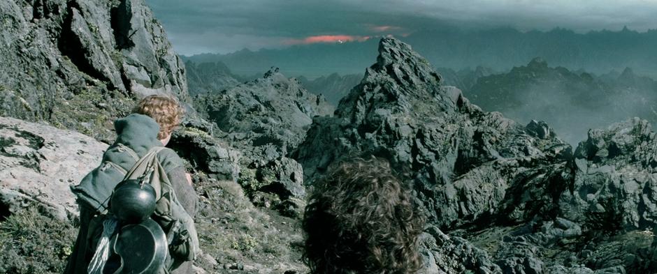 Frodo and Sam look at the mountains of Mordor in the distance.