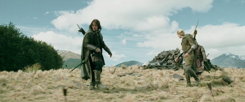 Aragorn, Gimli, and Legolas search for signs of the Hobbits by the pile of orc corpses.