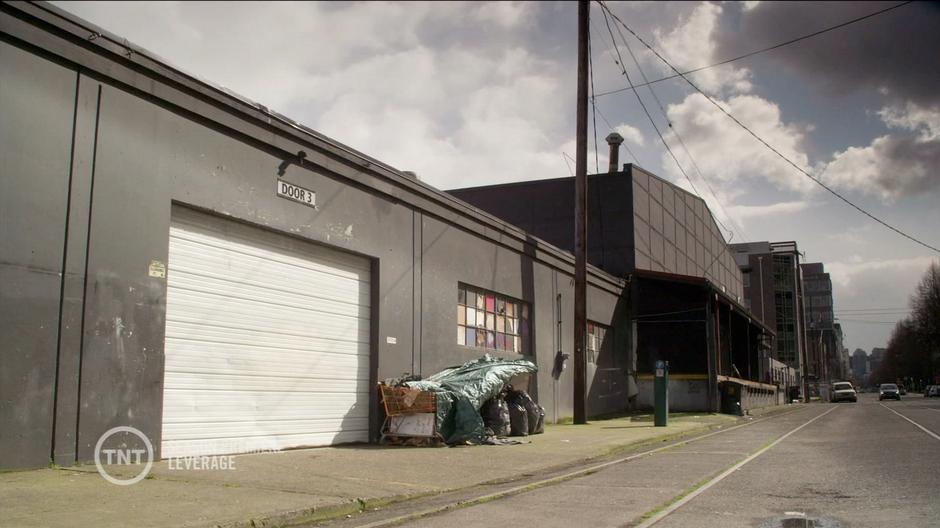 Establishing shot of the warehouse where the meeting takes place.