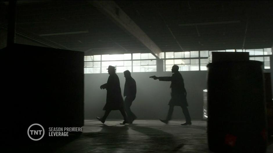 Hardison (in character) leads Nate and Scott Roemer out of the warehouse at gunpoint.
