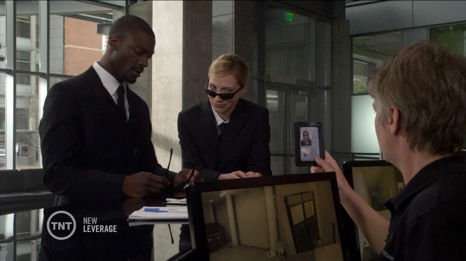 Parker and Hardison check in at the front desk in the guise of FBI agents.
