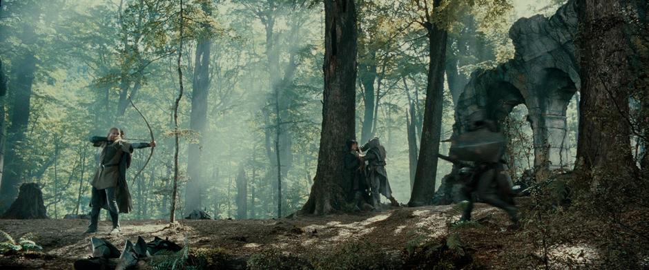 Legolas shoots an orc while Aragorn struggles with another one in the background.