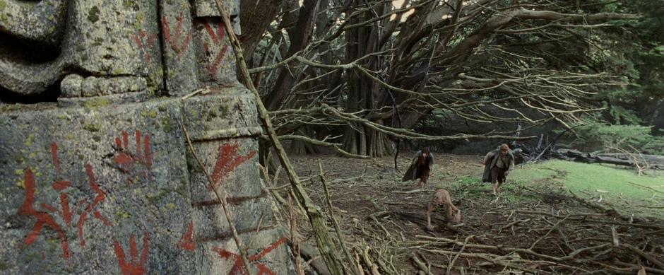Sam, Frodo, and Gollum come upon a vandalized statue in the woods.