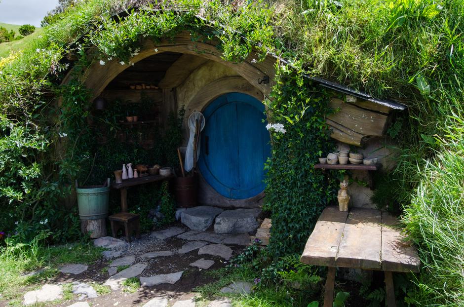 View of a small Hobbit-hole featuring a blue door with a butterfly net next to it.