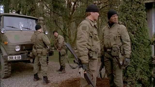 Jack and Teal'c talk about the situation while Charles Kawalsky and the other soldiers prepare behind them.