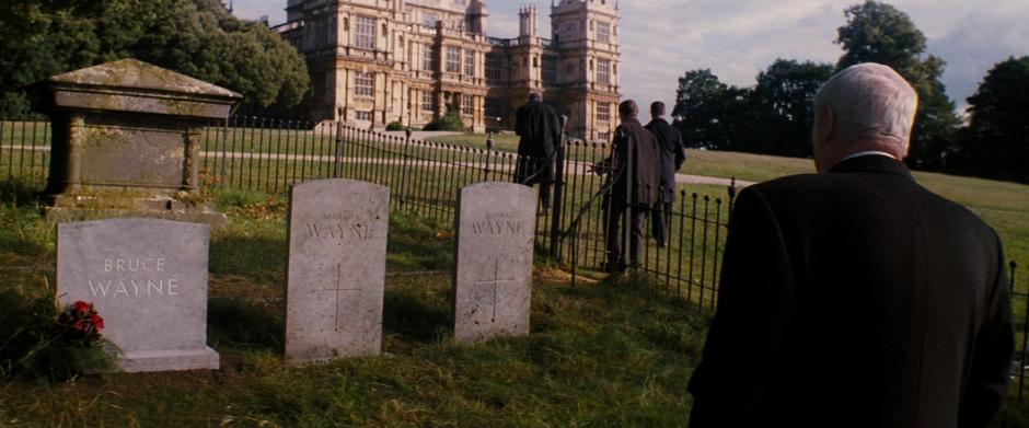 Alfred looks down at Bruce's grave while Gordon, Fox, and Blake walk back to the manor.