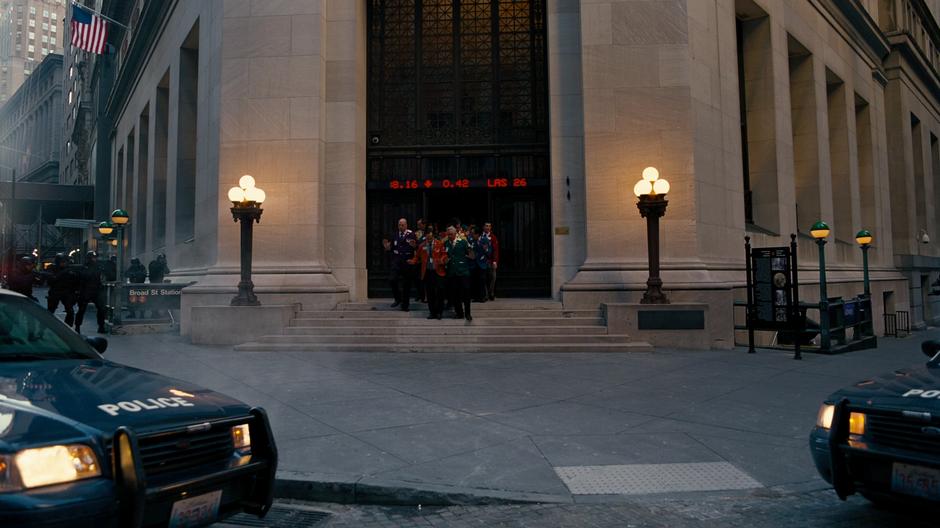 Bane's men lead the GSE hostages out of the building while being surrounded by the police.
