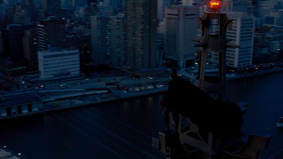 Batman stands atop the bridge and looks down on the city.