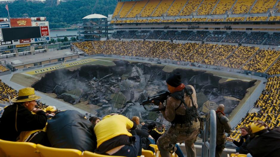 Bane's thugs watch the spectators while the destroyed field settles into the ground.