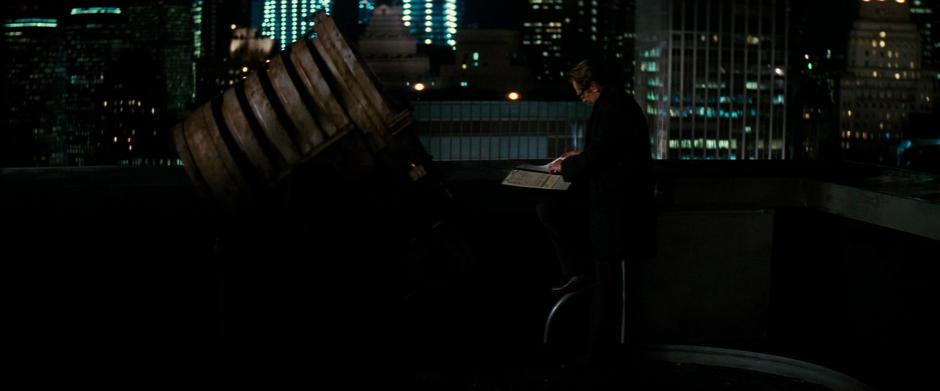 Gordon reads a report next to the old Bat-Signal.