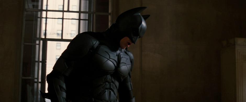 Batman looks down at Bane as he struggles to breath through his damaged mask.