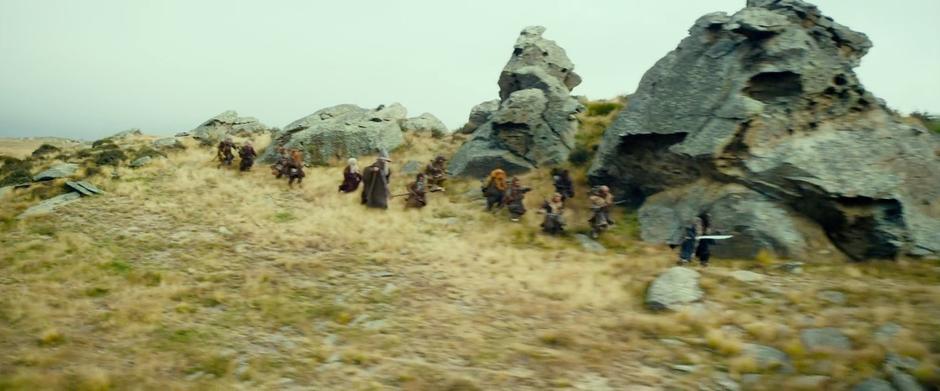The adventuring party runs from the orcs and wargs amongst some strange rock formations.