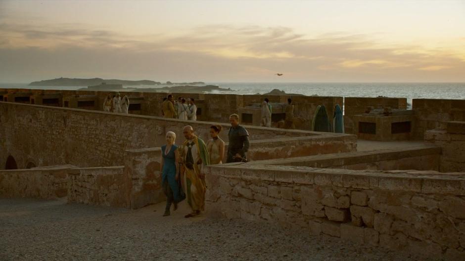 Ser Jorah follows with the translator while Daenerys talks to the slave seller.
