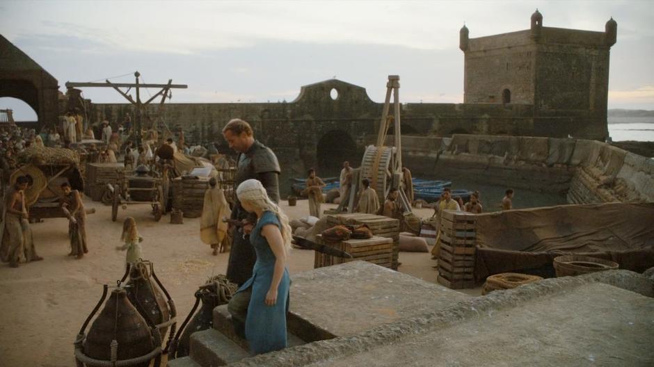 Daenerys and Ser Jorah walk down into the market by the harbour.