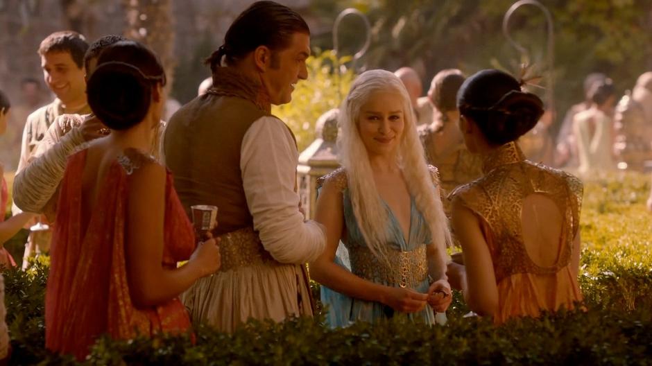 Daenerys smiles at Bronn from across the party.